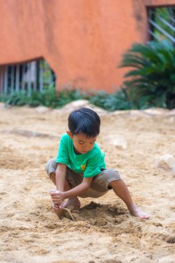 Sevimli küçük anaokulu çocuğu dışarıda kumlu çocuk parkında eğleniyor.