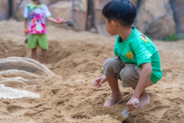 Sevimli küçük anaokulu çocuğu dışarıda kumlu çocuk parkında eğleniyor.