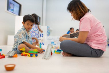 Çocuklu anne, erkek ve kız öğreniyor. Renkli oyuncak bloğu yapıyor. Sınıf eğitimi konseptinde.