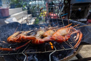 Dev nehir karidesleri ateşte kızartılıyor ve ev yapımı Asya deniz ürünleri pişiriliyor.