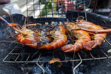 Dev nehir karidesleri ateşte kızartılıyor ve ev yapımı Asya deniz ürünleri pişiriliyor.