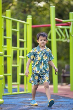 Çocuk parkında koşan küçük, mutlu bir okul çocuğu.