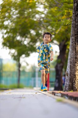 Çocuk parkında koşan küçük, mutlu bir okul çocuğu.