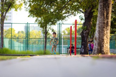 Çocuk parkında koşan küçük, mutlu bir okul çocuğu.