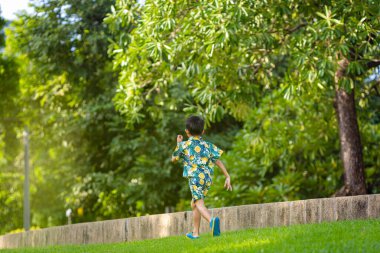 Çocuk parkında koşan küçük, mutlu bir okul çocuğu.