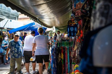 Mae Klong, Tayland. 15 Haziran 2024. Turistler, Tayland 'daki Mae Klong Tren Marketi' nde taze yiyecek satan Tayland market simsarlarının trendeki şemsiyesini kapatmak için eşsiz bir turizm merkezi olan Talad Rom Hub Pazarı boyunca dolaşıyorlar..