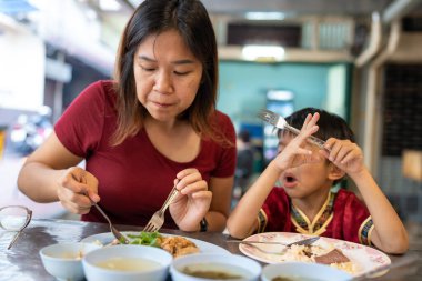 Annesiyle birlikte küçük Asyalı çocuk Yaowarat Bangkok Tayland 'da sokak yemeklerinde pilav yiyor.