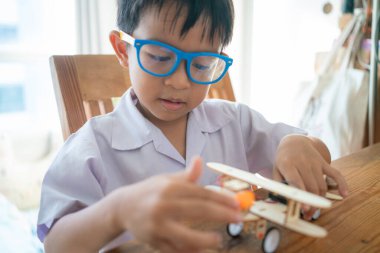 Küçük liseli çocuk, sınıfta elektronik öğrenen uçak roboy oyuncağı monte ediyor.