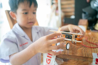 Küçük liseli çocuk, sınıfta elektronik öğrenen uçak roboy oyuncağı monte ediyor.