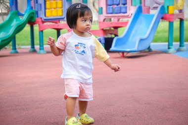 Sevimli çocuk. 2 yaşında kız. Şehir parkında yaz tatili için yürüyüş antrenmanı yapıyor.