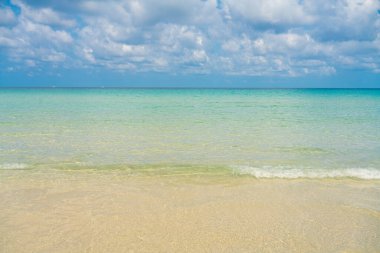 Beyaz kumlu deniz plajı dalgaları mavi gökyüzü bulutlu yaz tatili arka planı