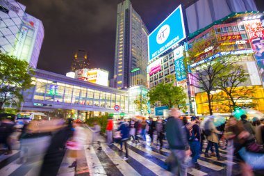 Shibuya Kavşağı 'nda gece vakti yürüyen insanların bulanık arka planı.