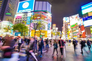Shibuya Kavşağı 'nda gece vakti yürüyen insanların bulanık arka planı.
