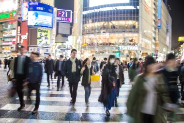 Shibuya Kavşağı 'nda gece vakti yürüyen insanların bulanık arka planı.
