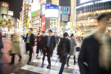 Shibuya Kavşağı 'nda gece vakti yürüyen insanların bulanık arka planı.