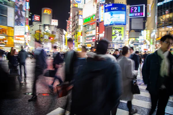 Shibuya Kavşağı 'nda gece vakti yürüyen insanların bulanık arka planı.
