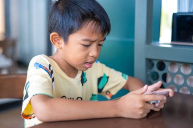 Küçük oğlan ve kız akıllı telefondan oyun oynuyorlar. Restorandaki çocuklar iletişim teknolojisiyle oturuyorlar.