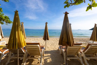 Yaz tatili arka planında kumlu deniz sahilinde boş bir plaj sandalyesi.