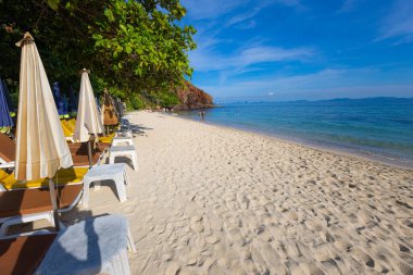 Yaz tatili arka planında kumlu deniz sahilinde boş bir plaj sandalyesi.