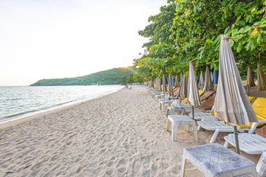 Yaz tatili arka planında kumlu deniz sahilinde boş bir plaj sandalyesi.