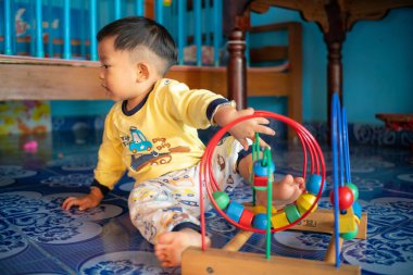 Küçük Asyalı 1-2 yaşındaki çocuk evde eğitim objesinde renkli ahşap oyuncaklar oynuyor.