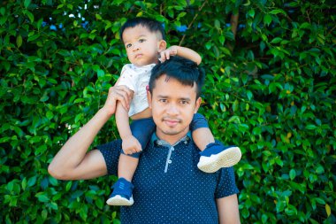 Şehir parkında babasının boynuna binen sevimli çocuk.