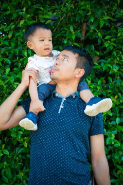 Şehir parkında babasının boynuna binen sevimli çocuk.