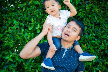 Şehir parkında babasının boynuna binen sevimli çocuk.