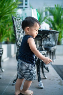 Yürüyen Asyalı çocuk parkta yürüme pratiği yapıyor. 1 yaşında bir çocuk.