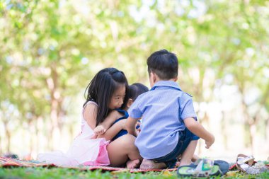 Şehir parkında oynayan bir grup mutlu anaokulu çocuğu ve kız.