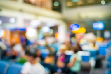 Bulanık insanlar havaalanı koltuğunda uçak yolculuğu için arka planda bekliyorlar.