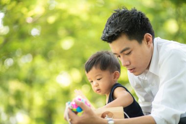 Küçük çocuk babasıyla yeşil şehir parkında oyun oynuyor.