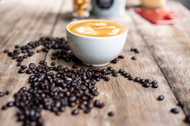 Kahve çekirdekli sıcak latte sanat kahvesi ahşap masa üzerinde içki içmek.