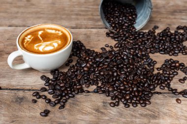 Kahve çekirdekli sıcak latte sanat kahvesi ahşap masa üzerinde içki içmek.