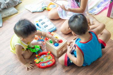 Çocuk grubu, çocuk odasının zemininde ahşap bir oyuncak tasarımcısıyla, odada oynayan çocuklarla oynuyor.