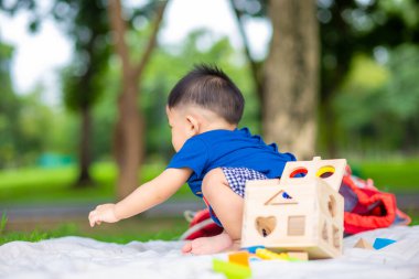 Gülümseyen Asyalı çocuk dışarıda yeşil çimen parkında oyuncak oynuyor.