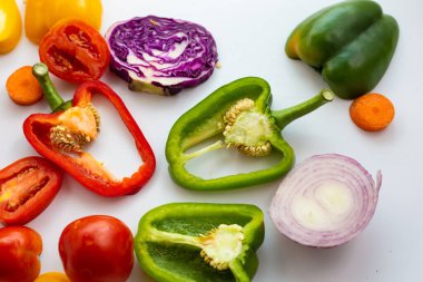 Beyaz arka plandaki vitamin yiyeceğinin üzerinde çeşitli sağlıklı sebzeler var.