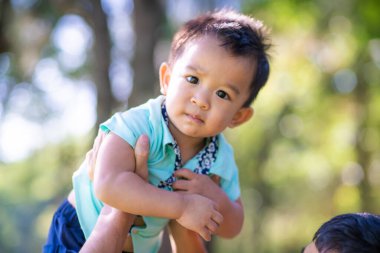 Baba, çocuğu elleriyle aldı. Parkta mutlu mesut eğleniyor.