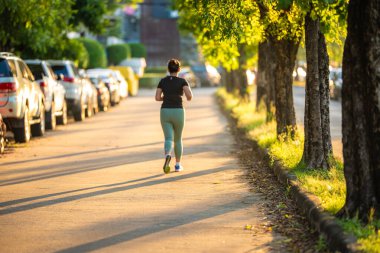 Güzel Asyalı sporcu aktif kadın şehir yolunda koşuyor. Sabah güneşi sağlıklı bir yaşam tarzı.