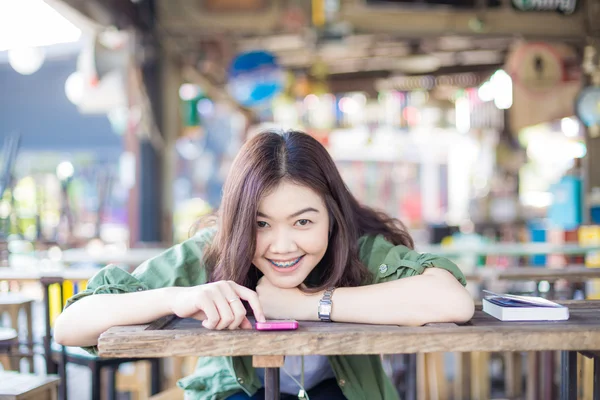 Charming asian girl sitting by wooden table and reading book — Stock Photo, Image