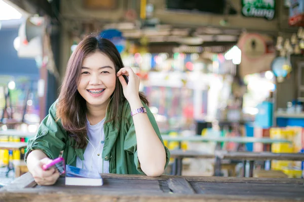 Asian woman reading a book while sitting on wooden table — Stock Photo, Image