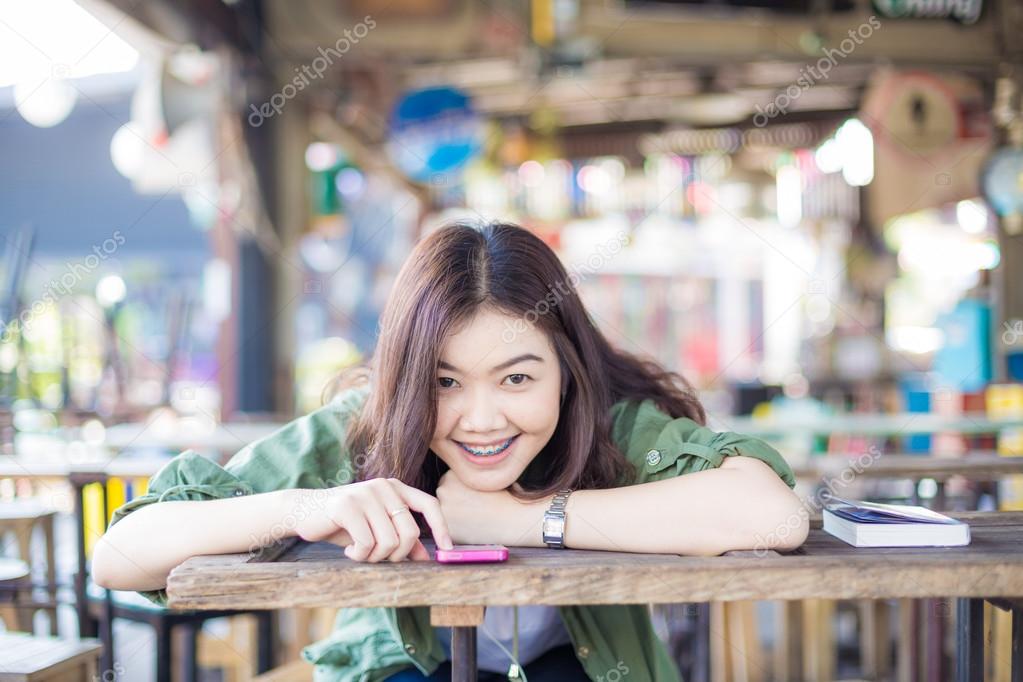 Charming asian girl sitting by wooden table and reading book