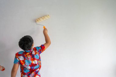 Küçük liseli çocuk duvarın içini boyamayı seviyor.