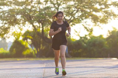 Spor Asyalı kadın şehri, gün doğarken yolda koşuyor. Sağlıklı bir yaşam tarzı.