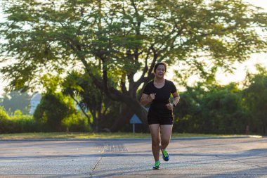 Spor Asyalı kadın şehri, gün doğarken yolda koşuyor. Sağlıklı bir yaşam tarzı.