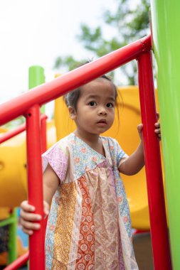 Sevimli küçük kız oyun parkına tırmanırken eğleniyor.