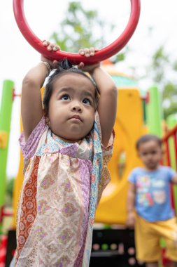 Sevimli küçük kız oyun parkına tırmanırken eğleniyor.
