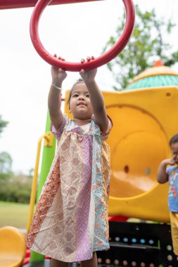 Sevimli küçük kız oyun parkına tırmanırken eğleniyor.