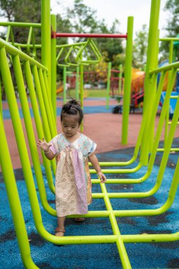 Sevimli küçük kız oyun parkına tırmanırken eğleniyor.