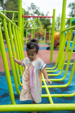 Sevimli küçük kız oyun parkına tırmanırken eğleniyor.